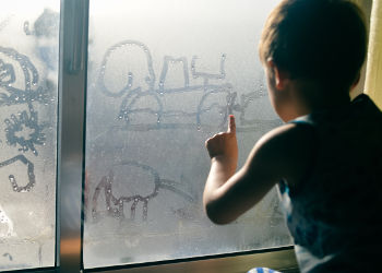 Enfant en contact avec de la condensation produite par l'humidité dans la maison